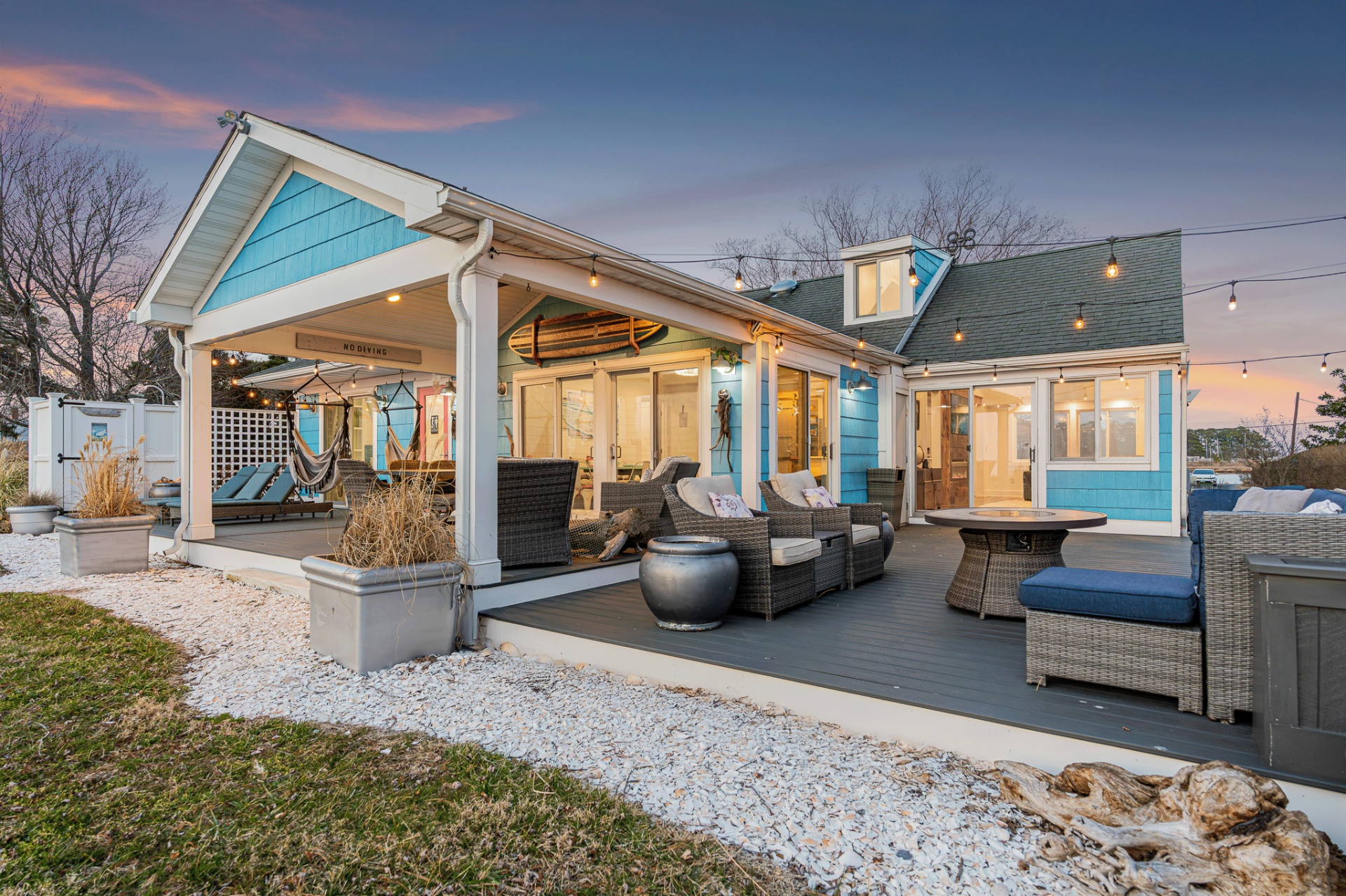 Blue coastal-style home with covered deck at dusk