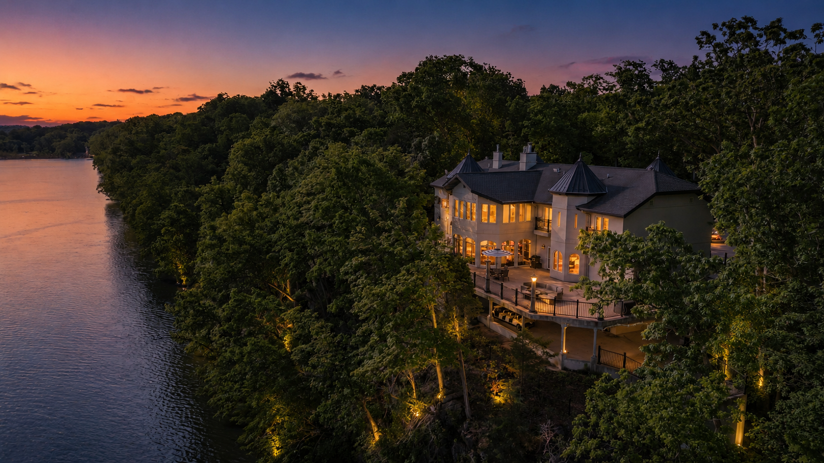 Riverfront estate at dusk with glowing windows