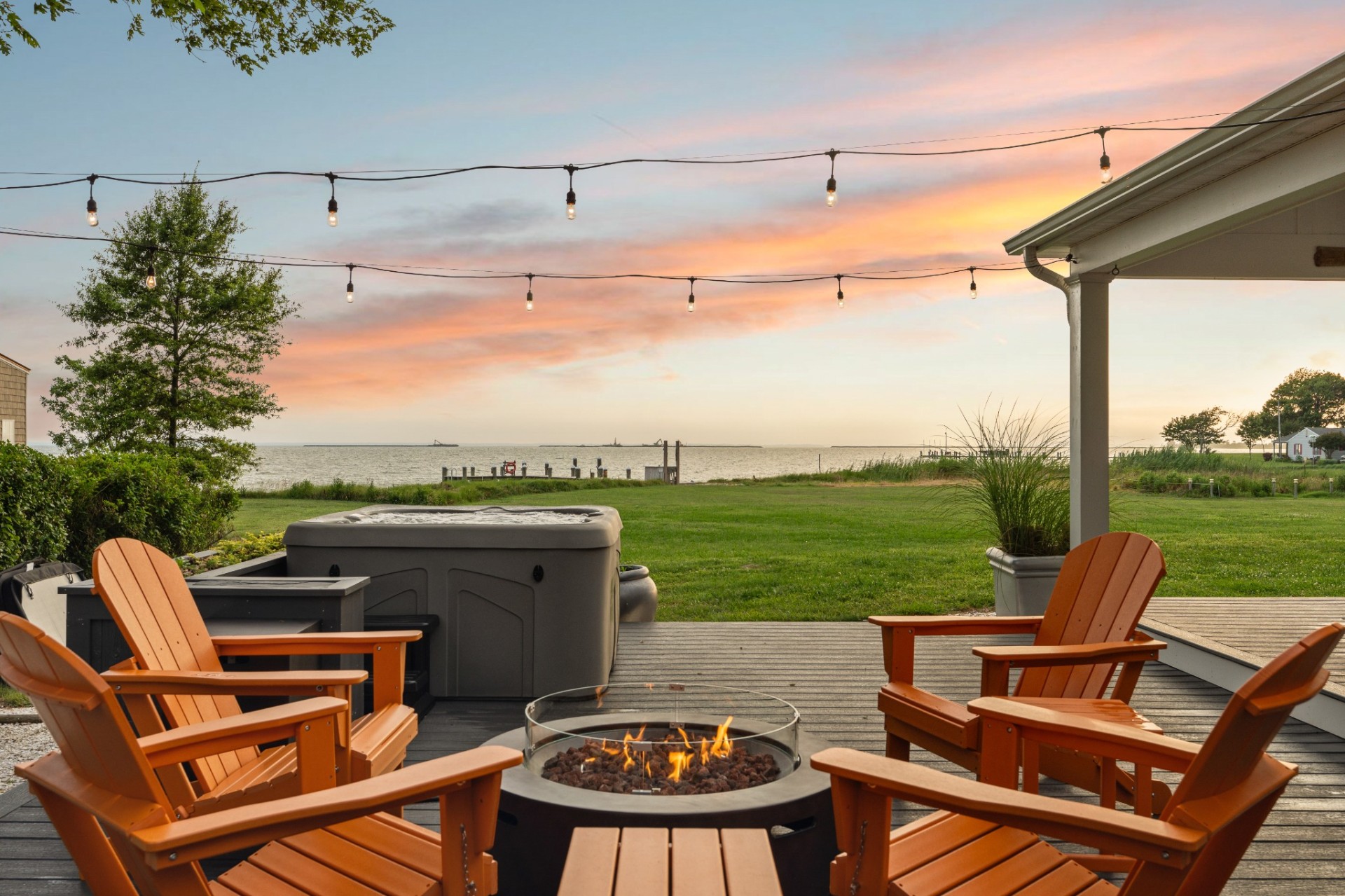 Bayfront deck with firepit and hot tub at sunset