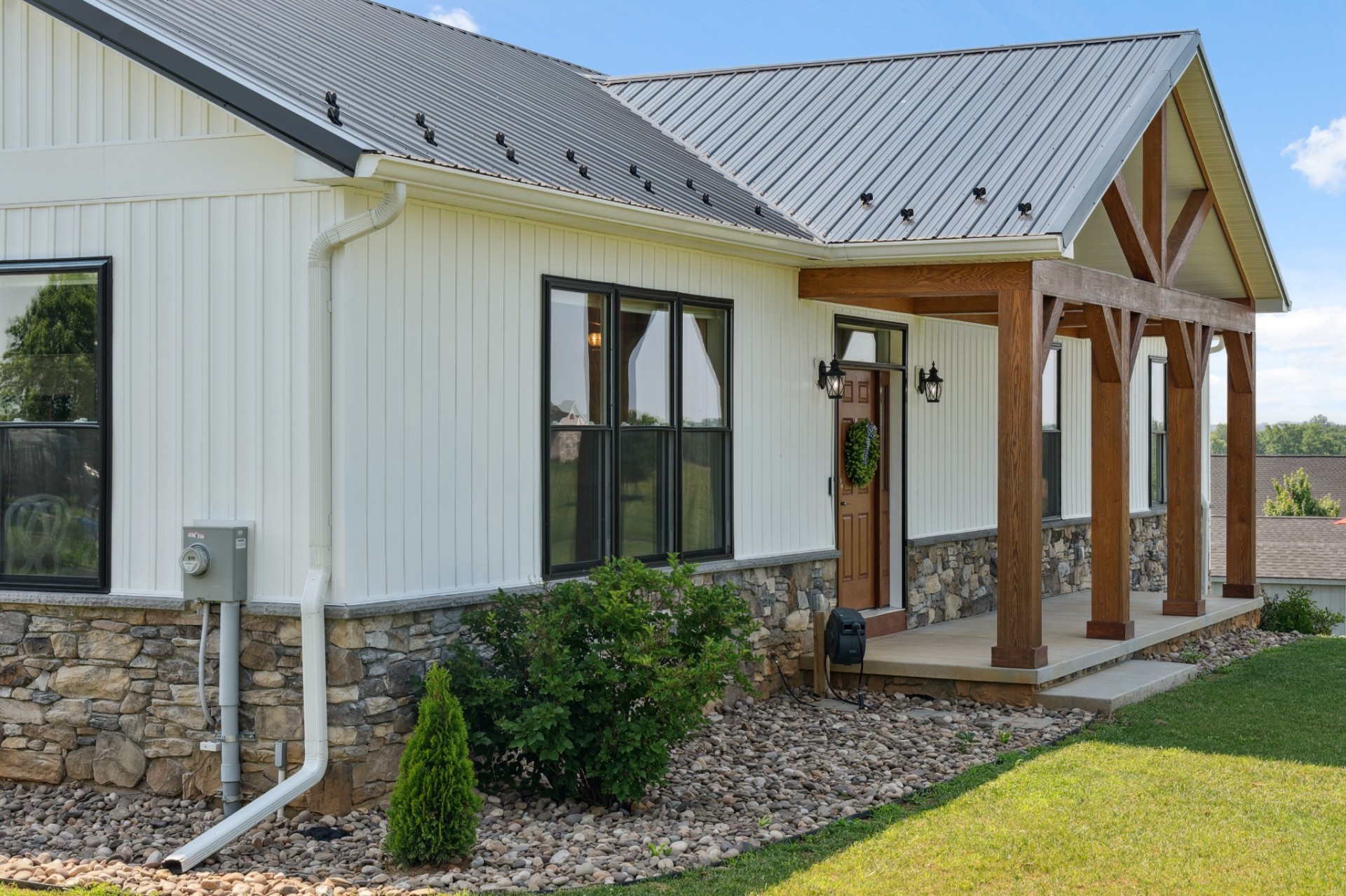 White farmhouse exterior with timber porch and stone base